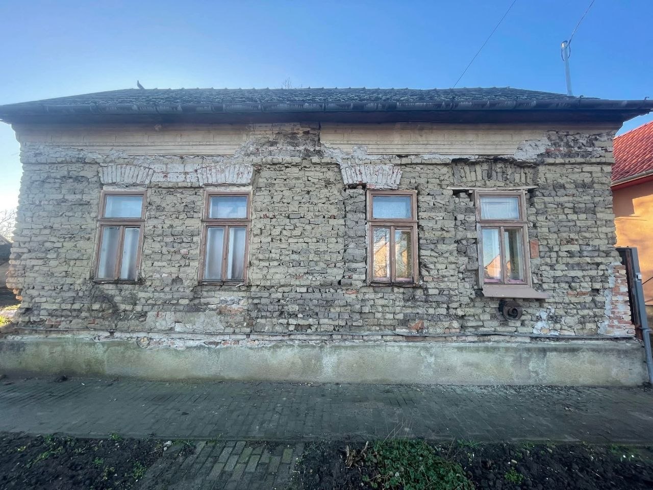 A ház a felújítás előtt: lehullott vakolat, látszó falazat és régi faablakok