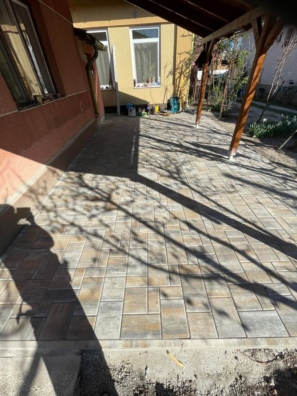 A kész térkő burkolat a fa tartóoszlopos nyitott teraszon, a ház falánál