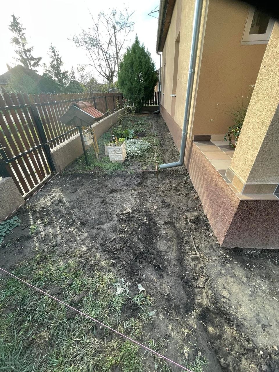 A térkövezés előtti kert: felásott, letisztított földterület a ház és a kerítés mellett