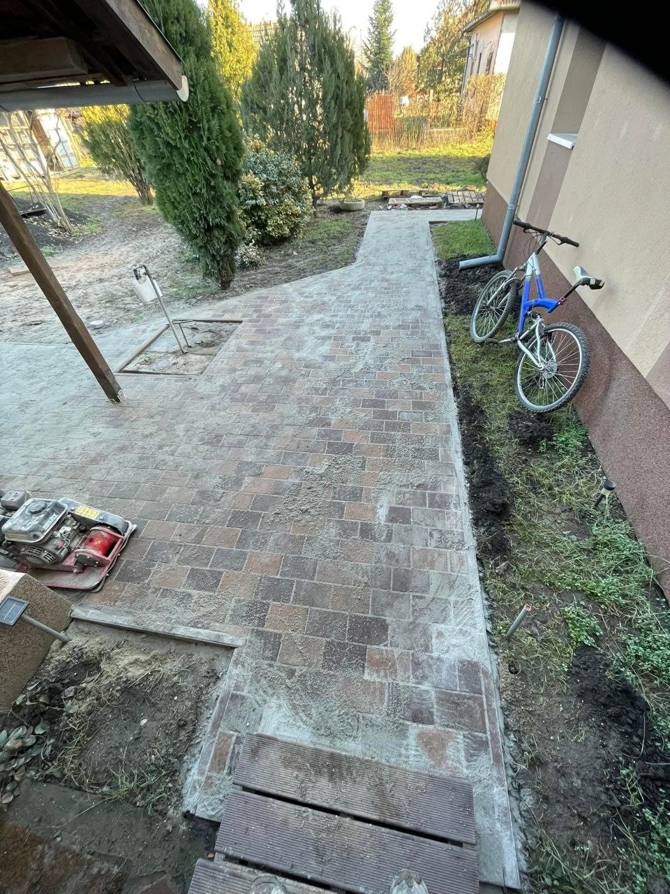 A járda egy része már letérkövezve, a végén még ágy és deszkák